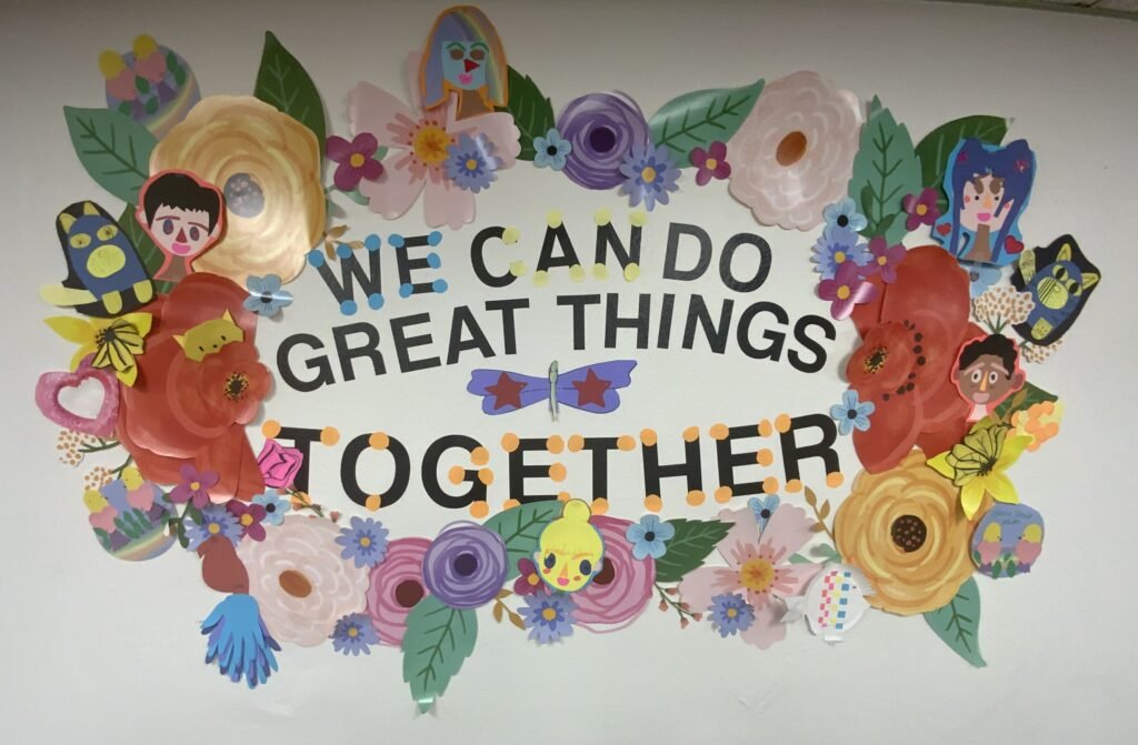Colorful wall display at API reading We Can Do Great Things Together