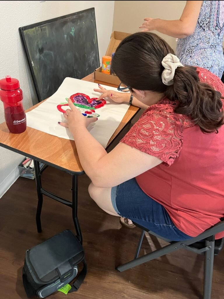 Participant painting a heart craft at a table during an activity