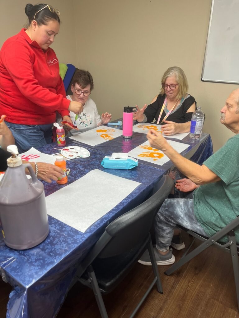 Participants and staff painting together at a table during Adult Day Training