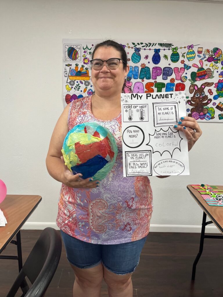 Participant proudly holding a handmade planet model and worksheet
