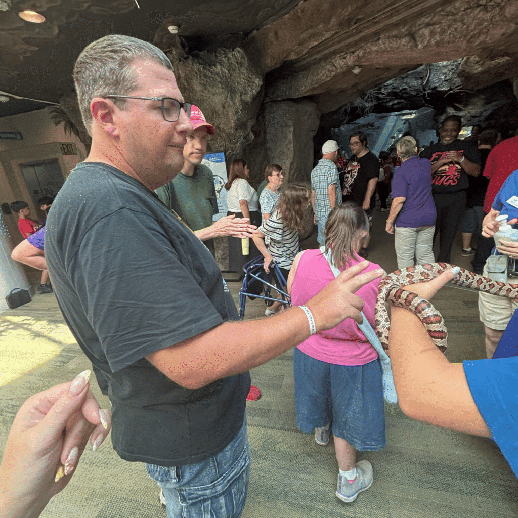 Participant meeting a snake held by a handler during an aquarium outing